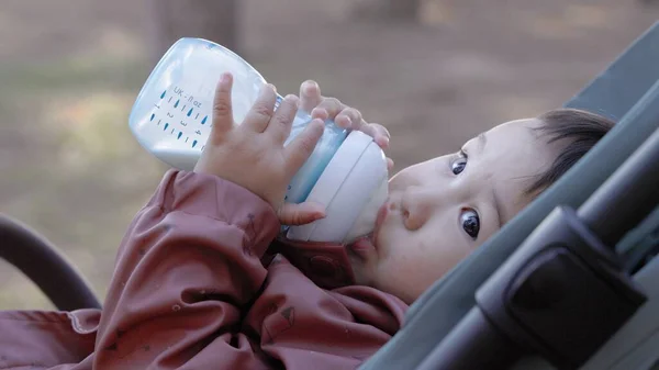 Asiatisches Baby Trinkt Formel Aus Einer Flasche Während Park Auf — Stockfoto