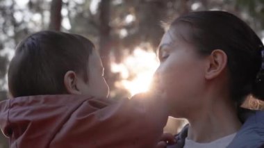Sevgi dolu bir anne kucağında bir bebek ve doğada şefkatle onu öpüyor. Yüksek kalite 4k görüntü