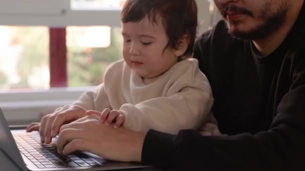 Ung Man Som Försöker Jobba Laptop Och Håller Sin Son — Stockvideo