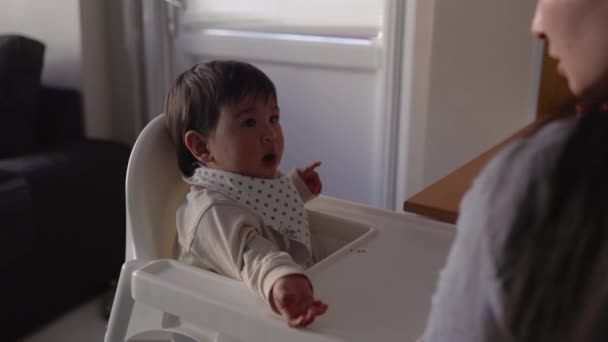 엄마가 아기에게 먹이는 뒷모습 어린아이는 의자에 숟가락으로 식사를 고품질 — 비디오