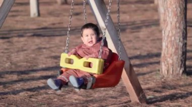 Parktaki güneşe doğru salıncakta sallanan bebek görüntüsü. Yüksek kalite 4k görüntü