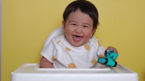 Bonito Bebê Asiático Senta Cadeira Alta Com Brinquedo Sorrindo Fundo — Vídeo de Stock