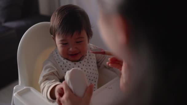 母親が赤ん坊に餌をやる姿を 幼児は高い椅子に座ってスプーンで食べています 高品質4K映像 — ストック動画