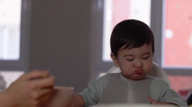 Anne bebeğini kaşıkla besliyor. Tamamlayıcı gıdaların tanıtımı, iyi beslenme, bebek maması yüksek kalite 4K görüntü