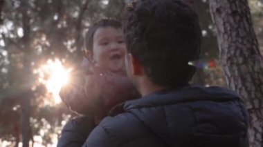 Sevgi dolu bir baba kucağında bir bebek ve doğada şefkatle onu öpüyor. Yüksek kalite 4k görüntü