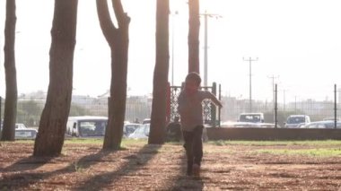Anaokulu çocuğu gün batımında parkta kameraya doğru koşuyor. Yüksek kalite 4k görüntü