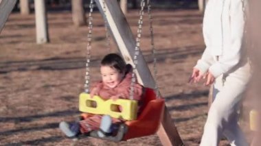 Parktaki güneşe doğru salıncakta sallanan bebek görüntüsü. Yüksek kalite 4k görüntü