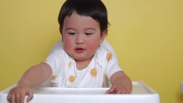 黄色い背景の上に可愛いアジア系の赤ちゃんが腰を下ろしています 高品質4K映像 — ストック動画