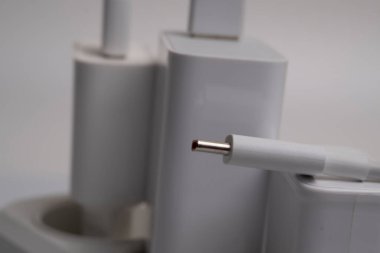Birçok şarj aleti beyaz arka plandaki bir elektrik prizine bağlıdır..