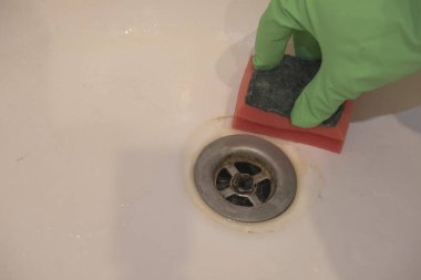 Eldivenli bir el banyodaki musluğu süngerle temizler. Temizlik kavramı