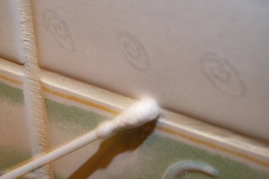 Eldivenli bir el banyodaki musluğu süngerle temizler. Temizlik kavramı