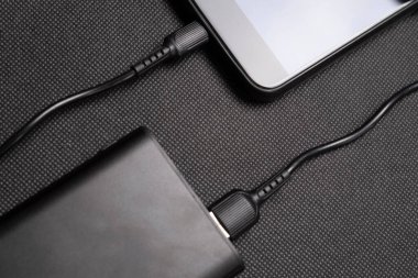 Güç bankasını şarj ediyorum. Şarj cep telefonu ya da akıllı telefon bataryası için beyaz USB kablosu olan taşınabilir güç bankası. Üst görünümde modern teknoloji kavramı