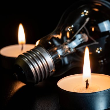 Arka planda elektrik lambası ve mum var. Parlayan lamba ve mum. Elektrik kesintisi yok. Yüksek elektrik fiyatları. Elektrik tasarrufu.