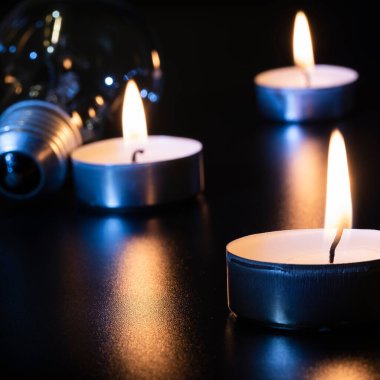 Arka planda elektrik lambası ve mum var. Parlayan lamba ve mum. Elektrik kesintisi yok. Yüksek elektrik fiyatları. Elektrik tasarrufu.