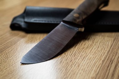 Siyah arka planda el yapımı avcı bıçağı. Deri kınalı el yapımı. Yüksek karbonlu çelik.