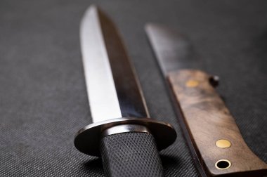 Siyah arka planda el yapımı avcı bıçağı. Deri kınalı el yapımı. Yüksek karbonlu çelik.