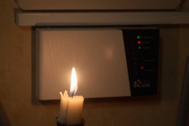 Elinde mum olan bir hırsız hırsız alarm sistemini devre dışı bırakmaya çalışıyor.