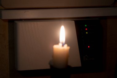 Elinde mum olan bir hırsız hırsız alarm sistemini devre dışı bırakmaya çalışıyor.