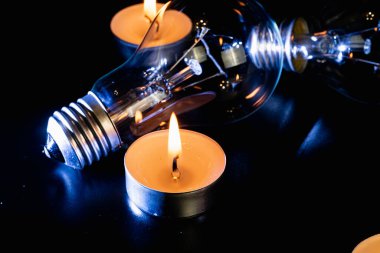 Arka planda elektrik lambası ve mum var. Parlayan lamba ve mum. Elektrik kesintisi yok. Yüksek elektrik fiyatları. Elektrik tasarrufu.
