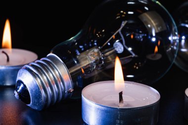 Arka planda elektrik lambası ve mum var. Parlayan lamba ve mum. Elektrik kesintisi yok. Yüksek elektrik fiyatları. Elektrik tasarrufu.
