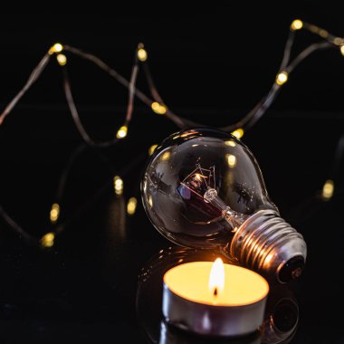 Ampuller ve yanan bir mum siyah bir arka planda. Aynı zamanda çelenk, bokeh. bayram karartması konsepti