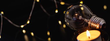 Ampuller ve yanan bir mum siyah bir arka planda. Aynı zamanda çelenk, bokeh. bayram karartması konsepti