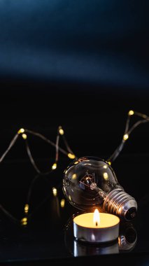 Ampuller ve yanan bir mum siyah bir arka planda. Aynı zamanda çelenk, bokeh. bayram karartması konsepti