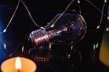 Ampuller ve yanan bir mum siyah bir arka planda. Aynı zamanda çelenk, bokeh. bayram karartması konsepti