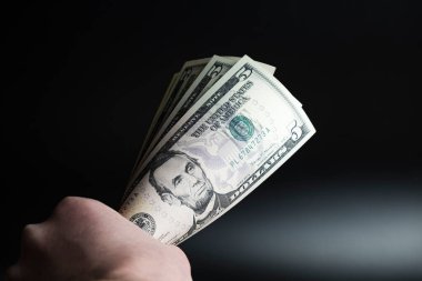 Siyah bir arkaplanda 5 dolar sıkıca tutulur. İşverenin ödemesi zordur.