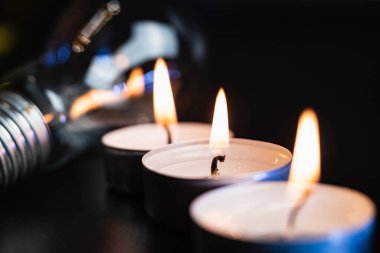 Arka planda elektrik lambası ve mum var. Parlayan lamba ve mum. Elektrik kesintisi yok. Yüksek elektrik fiyatları. Elektrik tasarrufu.