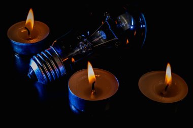 Arka planda elektrik lambası ve mum var. Parlayan lamba ve mum. Elektrik kesintisi yok. Yüksek elektrik fiyatları. Elektrik tasarrufu.