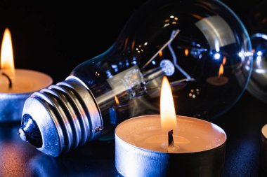Arka planda elektrik lambası ve mum var. Parlayan lamba ve mum. Elektrik kesintisi yok. Yüksek elektrik fiyatları. Elektrik tasarrufu.