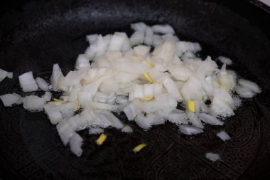 To cook. Homemade food.Pieces of fried onions and carrots in a frying pan. Chopped onions and grated carrots are fried on the stove. Selective focus.