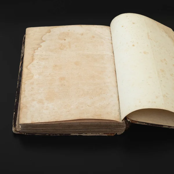 Top view of an old open book with blank pages on a dark background as copy space, retro toned image.Open book on dark background