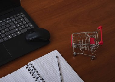 Online shopping. Supermarket cart on open laptop. E-commerce, buying goods or services over the Internet, buying goods in online stores using the concept of digital technology.