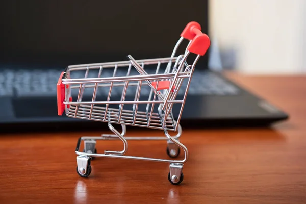 Online shopping. Supermarket cart on open laptop. E-commerce, buying goods or services over the Internet, buying goods in online stores using the concept of digital technology.