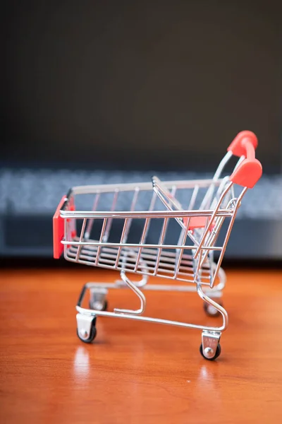 Online shopping. Supermarket cart on open laptop. E-commerce, buying goods or services over the Internet, buying goods in online stores using the concept of digital technology.