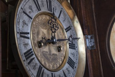 Old wooden clock with a pendulum hanging on the wall