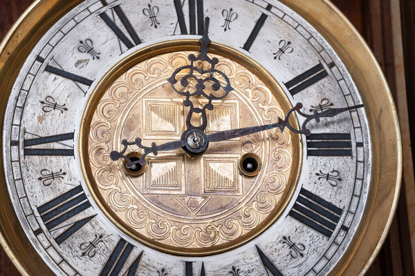 Old wooden clock with a pendulum hanging on the wall