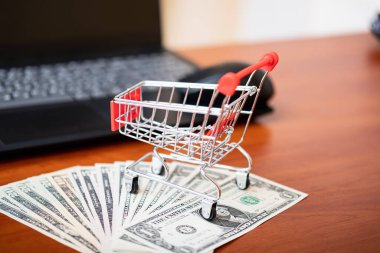 Online shopping concept. Us basket and dolors, laptop on the table