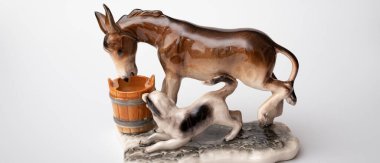 figurine of a donkey that drinks water and next to it a dog teases a donkey