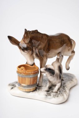 figurine of a donkey that drinks water and next to it a dog teases a donkey