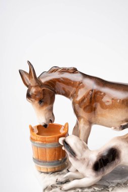 figurine of a donkey that drinks water and next to it a dog teases a donkey