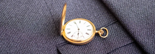 Golden pocket watch on the background of a man\'s suit.Retro style and vintage fashion.