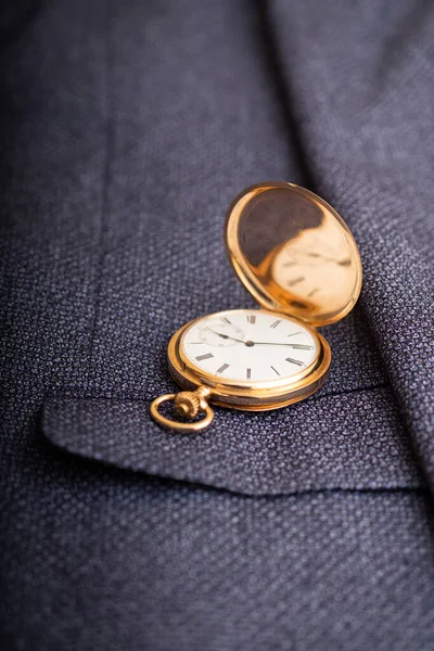 Golden pocket watch on the background of a man's suit.Retro style and vintage fashion.