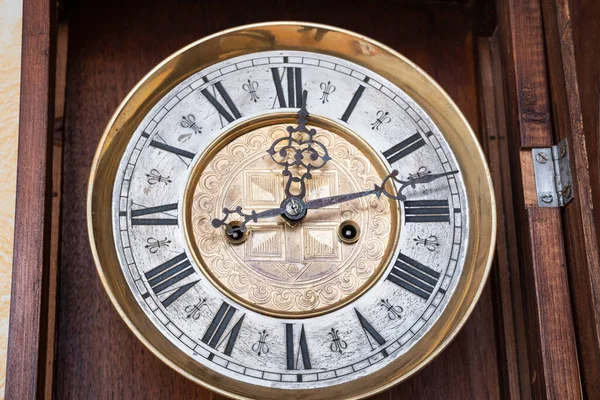 Old wooden clock with a pendulum hanging on the wall
