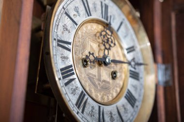 Old wooden clock with a pendulum hanging on the wall