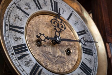 Old wooden clock with a pendulum hanging on the wall