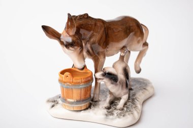 figurine of a donkey that drinks water and next to it a dog teases a donkey