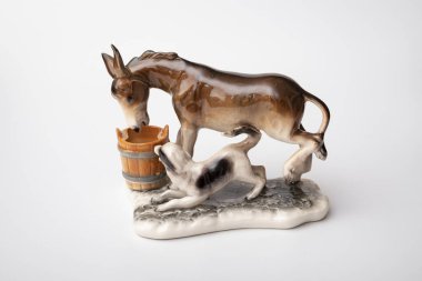 figurine of a donkey that drinks water and next to it a dog teases a donkey